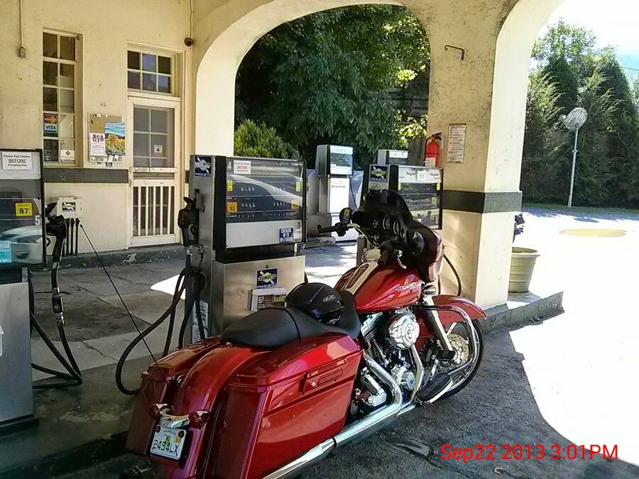 Red touring motorcycle stopped beside a fuel pump.