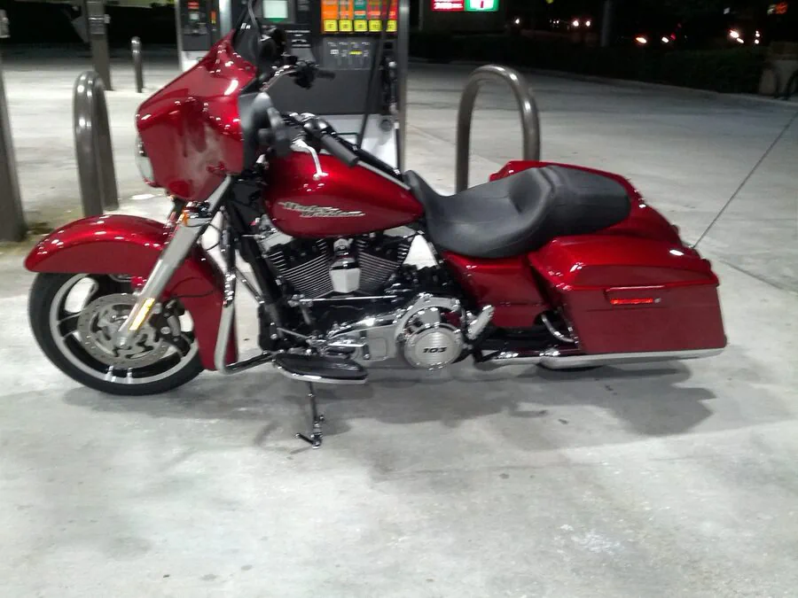 Red touring motorcycle parked beside a fuel pump.