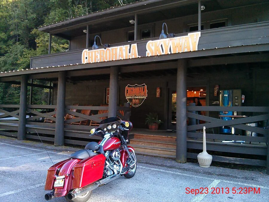 Red touring motorcycle beneath a Cherohala Skyway sign.